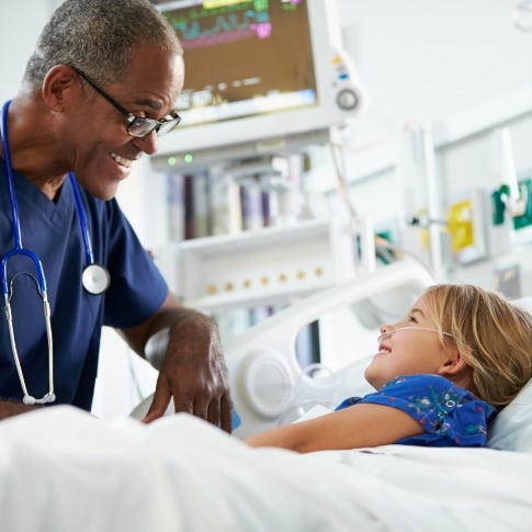 Dentist talking to young dental patient in hospital bed