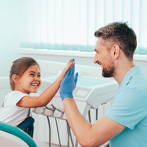 Smiling child giving dentist high-five