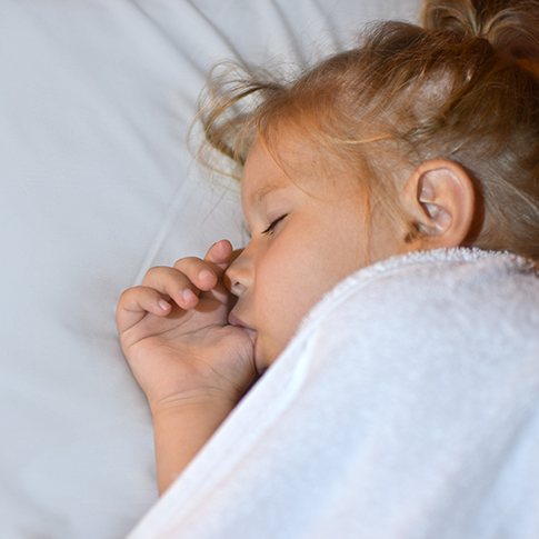 Child sucking their thumb while sleeping