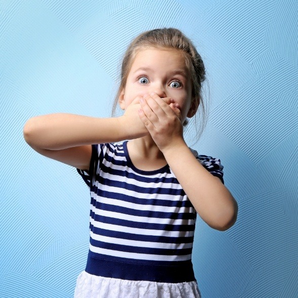 Child covering mouth before pediatric emergency dentistry