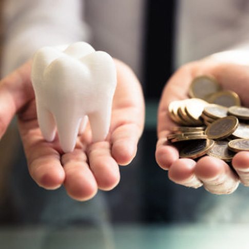 someone holding coins and a fake tooth  