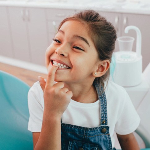 a child pointing toward her teeth   