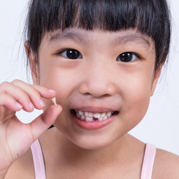 a young girl holding a tooth