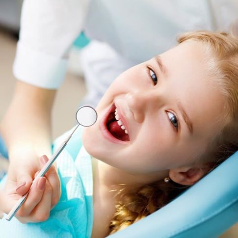 a child smiling while visiting her dentist