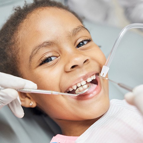 Child smiling while getting tooth-colored filling in Worcester