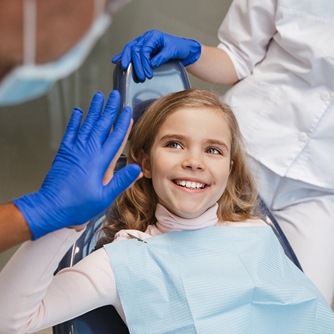 Child smiling and giving dentist a high five