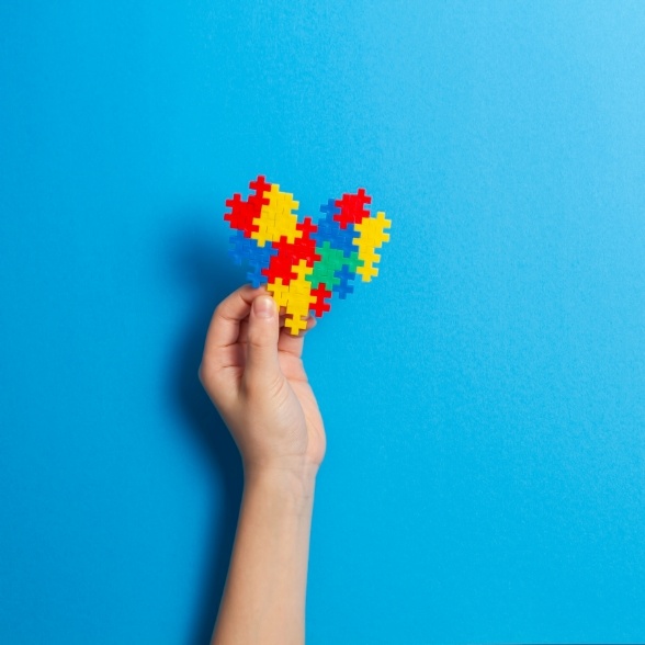 Child holding up a heart made of puzzle pieces representing special needs dentistry