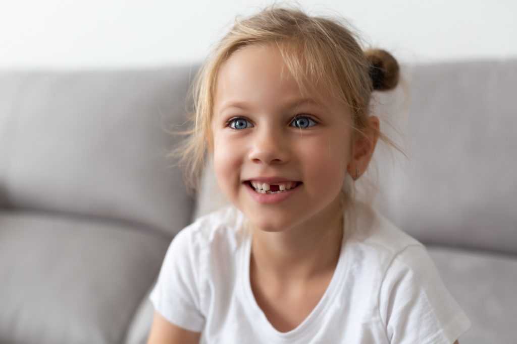 Young girl with missing tooth smiling