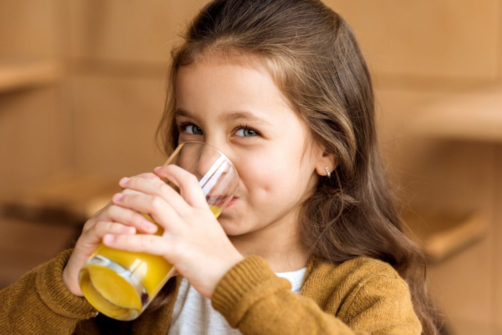 Young girl smiling while drinking juice