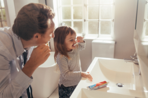 a parent helping their child brush their teeth