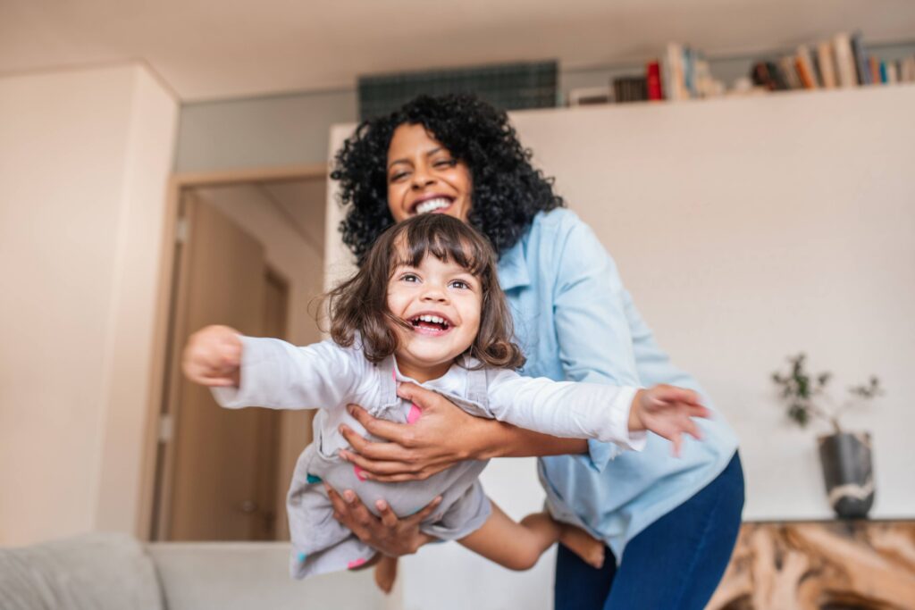 Smiling mom and daughter playing at home