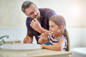 a parent helping their child brush their teeth