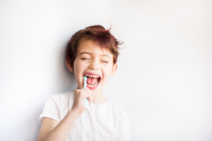 a child smiling while brushing their teeth
